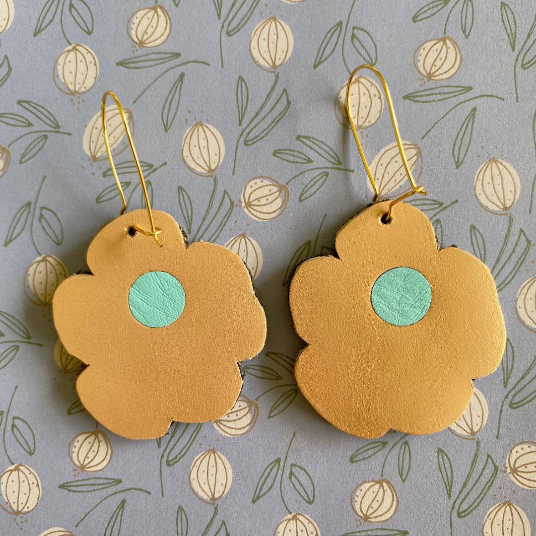 Aretes de cuero recuperado reversibles en forma de margarita. Diseño costarricense. Joyería artesanal contemporánea sostenible. Joyería de autor.