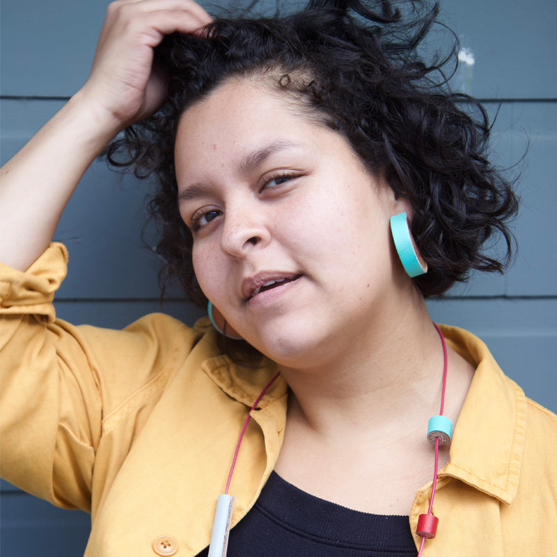 Mujer usando aretes de madera con cuero turquesa