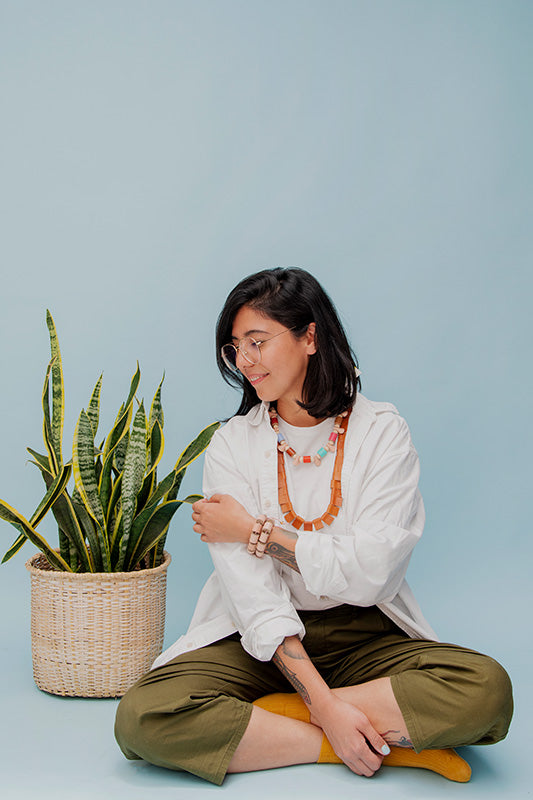 Mujer con blusa blanca usando el collar trópico de cuero color miel