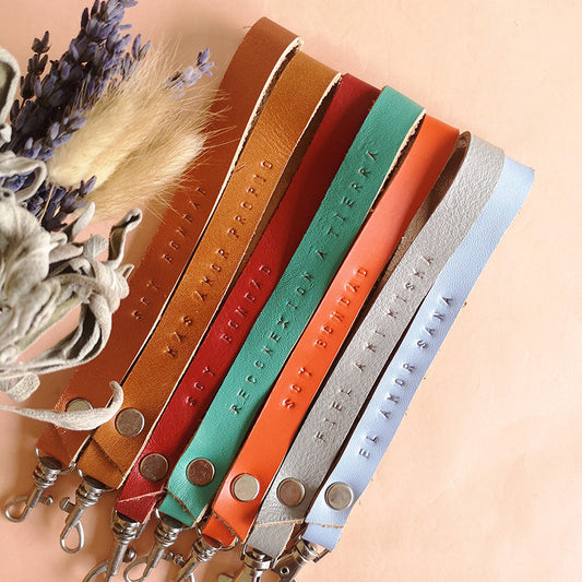 Llaveros de retazos de cuero de diferentes colores estampados con frases a mano
